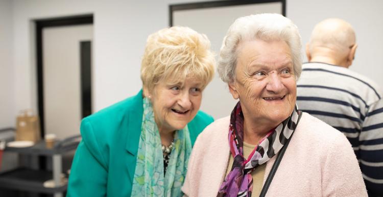 Two elderly women having a giggle together